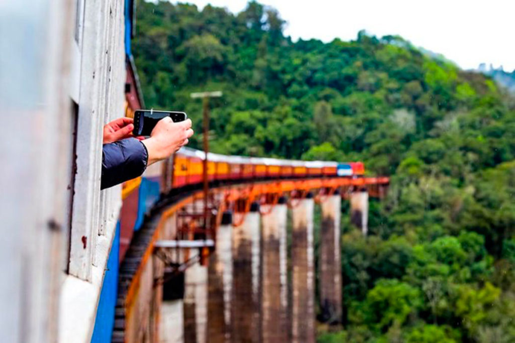 Turista coloca câmera para fora da janela do Trem dos Vales